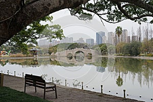 Scenic park bench situated beside a tranquil pond and bridge in Wenzhou city China