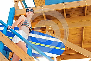 Scenic portrait young adult beautiful slim sporty woman with surfboard go downstairs from vintage wooden safety rescue