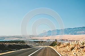 Scenic road by the sea in Croatia leading to Pag, on island, with mountains in the background