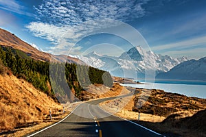 Scenic road winding its way along the shores of the alpine Lake Pukaki with Mt Cook in the background