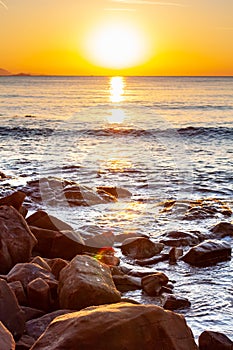 Scenic rocky beach Cala Violina landscape at the sunset. The sun is going down behind the horizon. Tyrrhenian Sea bay at the