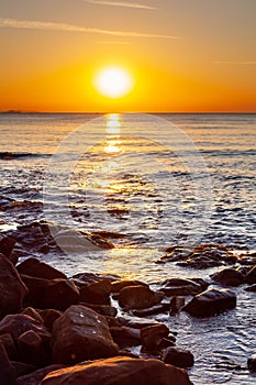 Scenic rocky beach Cala Violina landscape at the sunset. The sun is going down behind the horizon. Tyrrhenian Sea bay at the