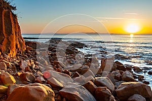 Scenic rocky beach Cala Violina landscape at the sunset. The sun is going down behind the horizon. Tyrrhenian Sea bay at the