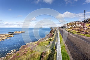 Scenic rural road in the lush grassy shoreline of Clashnessie Bay, in Scotland