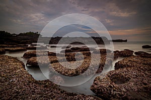 Scenic seascape for background. Beach with rocks and stones. Low tide. Blurred foggy water. Cloudy sky. Slow shutter speed. Soft