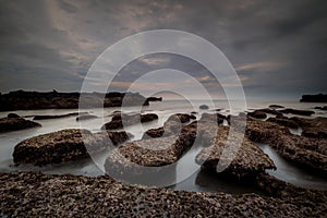 Scenic seascape for background. Beach with rocks and stones. Low tide. Blurred foggy water. Cloudy sky. Slow shutter speed. Soft