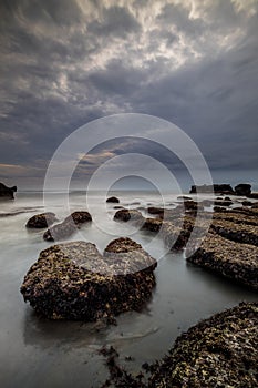 Scenic seascape for background. Beach with rocks and stones. Low tide. Blurred foggy water. Cloudy sky. Slow shutter speed. Soft