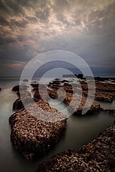 Scenic seascape for background. Beach with rocks and stones. Low tide. Blurred foggy water. Cloudy sky. Slow shutter speed. Soft