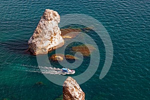 Scenic seascape of rocks in Black Sea with clear azure water and travel boat viewed from