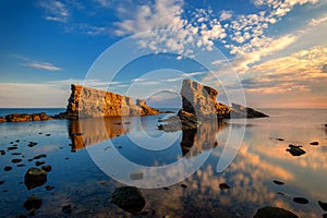 Scenic seascape shot at sunset with nice clouds, water reflection and long exposed waves