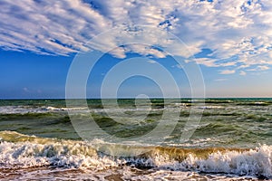 Scenic seascape with surfing waves breaking onto sandy Black sea shore by Anapa on sunny day