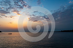 Scenic shot of the calm sea with sailing boats and the evening sun setting on the horizon in Croatia