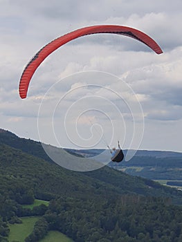 Scenic shot of a man skydiving over a mountain