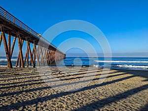 Scenic shot of the reflection of Rosarito Pier on the sand on a sunny day, Mexico photo