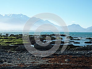 Scenic shot of a rocky seashore with a foggy mountain on the background