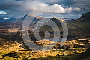 Scenic shot of the Scotland Quiraing landslip with mountains and a small lake below a cloudy sky