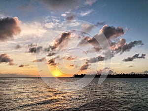 Scenic shot of the sea against the green coast at vivid sunset