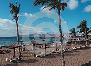 Scenic shot of thatched umbrellas and sunloungers on the shore of a sea in a resort