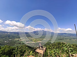 Scenic shot of three people standing at the viewpoint over a green countryside