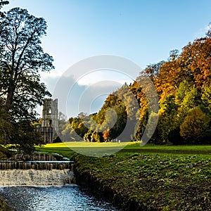 Scenic shot of the trees, grass fields, and a river near the Fountains Abbey in Ripon, UK