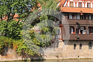 Scenic shot of trees near a big building on the bank of a river in an Old town of Nuremberg, Germany