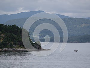 Scenic shot of two small fishing boats floating in a Norwegian fjord next to a small boat shed