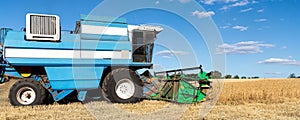 Scenic side view Big powerful industrial combine harvester machine reaping golden ripe wheat cereal field on bright