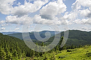 Scenic skyscape with blue sky full of windy clouds, and beautiful green mountains. Carpathians, Ukraine