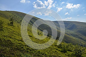 Scenic skyscape with blue sky full of windy clouds, and beautiful green mountains. Carpathians, Ukraine