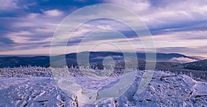Scenic snowy landscape with a view from a mounatin summit to the valey and mountain range