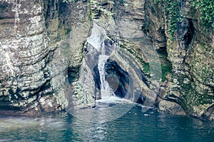 A scenic stream of a waterfall falling among a rocky gorge. Agur river in Khosta microdistrict, Russia. Travelling, hiking and