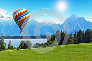 Scenic summer landscape with hot air balloon, lake and mountains