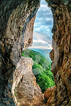 Scenic summer vertical landscape view of mountain forest from inside weird rocky grotto in Caucasus mountains, Lenina Rock shelf,