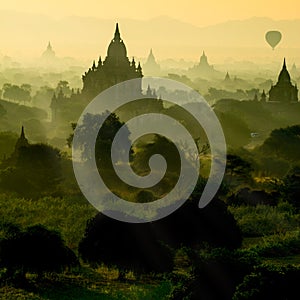 Scenic sunrise with silhouette balloons above ruin pagoda in Bagan, Myanmar.