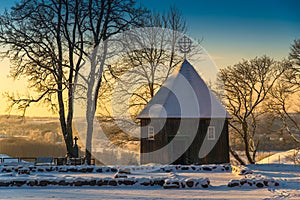 Scenic sunrise winter landscape of wooden chapel and snowy trees