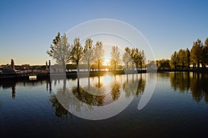 Scenic sunset landscape near embankment in the Taras Shevchenko Park in Ternopil. Sun and trees reflected in the tranquil water.