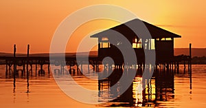 Scenic sunset over the fishermen tent and wooden pier with fishing nets in the sea lake water