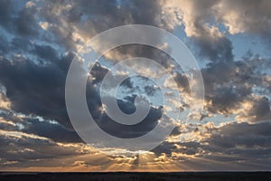 Sunset over the forest with sun rays breaking through clouds