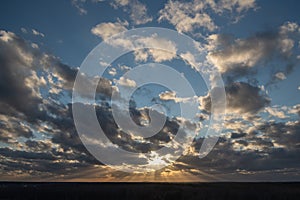 Sunset over the forest with sun rays breaking through clouds