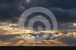 Sunset over the forest with sun rays breaking through clouds