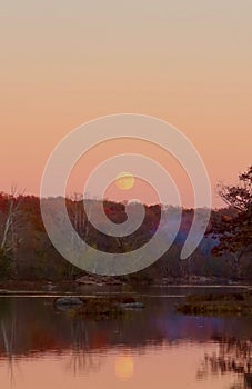 Scenic sunset over a lake surrounded by the forest in autumn