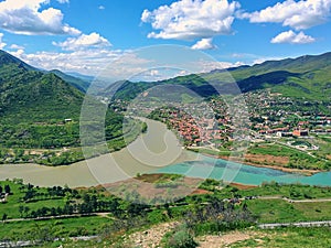 Scenic top view to old georgian  small town located at valley of confluence two mountain rivers with different colors of water.