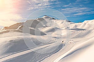 Scenic valley of hilghland alpine mountain winter resort on bright sunny day. Wintersport scene with people enjoy skiing