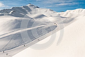 Scenic valley of hilghland alpine mountain winter resort on bright sunny day. Wintersport scene with people enjoy skiing photo