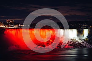 Scenic view of American Falls illuminated with lights in Niagara Falls in Ontario, Canada, at night