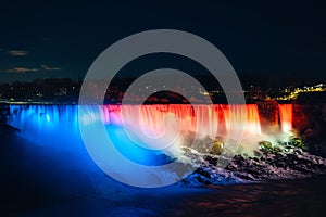 Scenic view of American Falls illuminated with lights in Niagara Falls in Ontario, Canada, at night