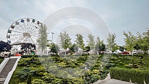 Scenic view of amusement park with Ferris wheel, green trees, and cloudy sky