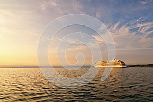 Scenic view of beautiful large white ship. Panoramic dramatic sunset sky. Ship glides out of the port of Koper