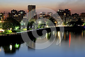 Scenic view of beautiful modern buildings, skyscrapers and towers of night big city are reflected in the Dnieper River in evening