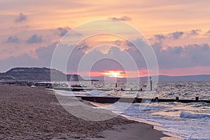 A scenic view of a beautiful sunrise at the beach with some hill in the background